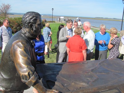 Close up of the Vernon Smith figure with his great grandson and donor Allen Eaves, wearing a grey jacket in the background.